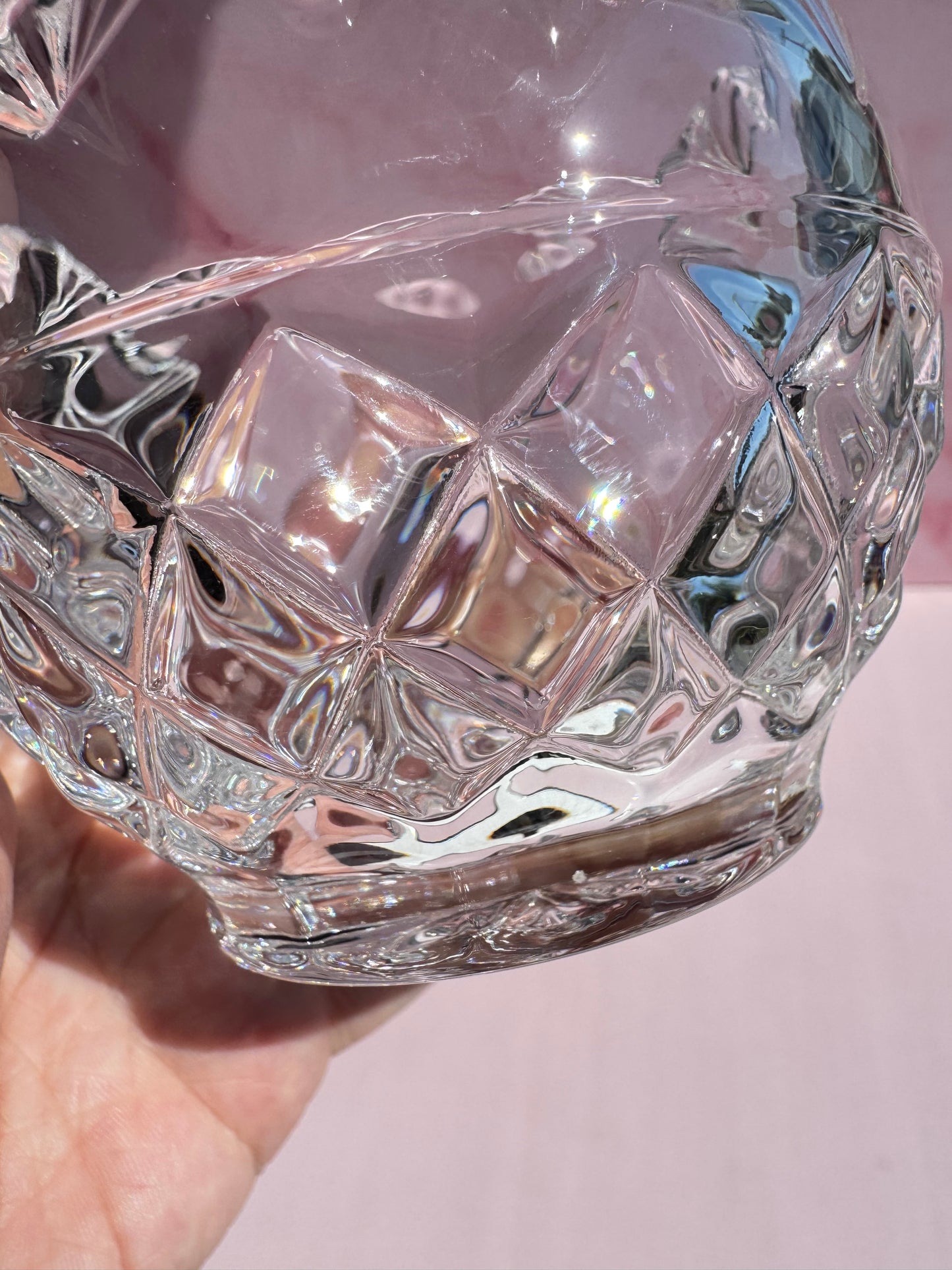 A close-up of the Cut Crystal Mini Glass Bowl with scalloped edges, held in sunlight to reveal reflections and geometric patterns across its faceted clear surface.