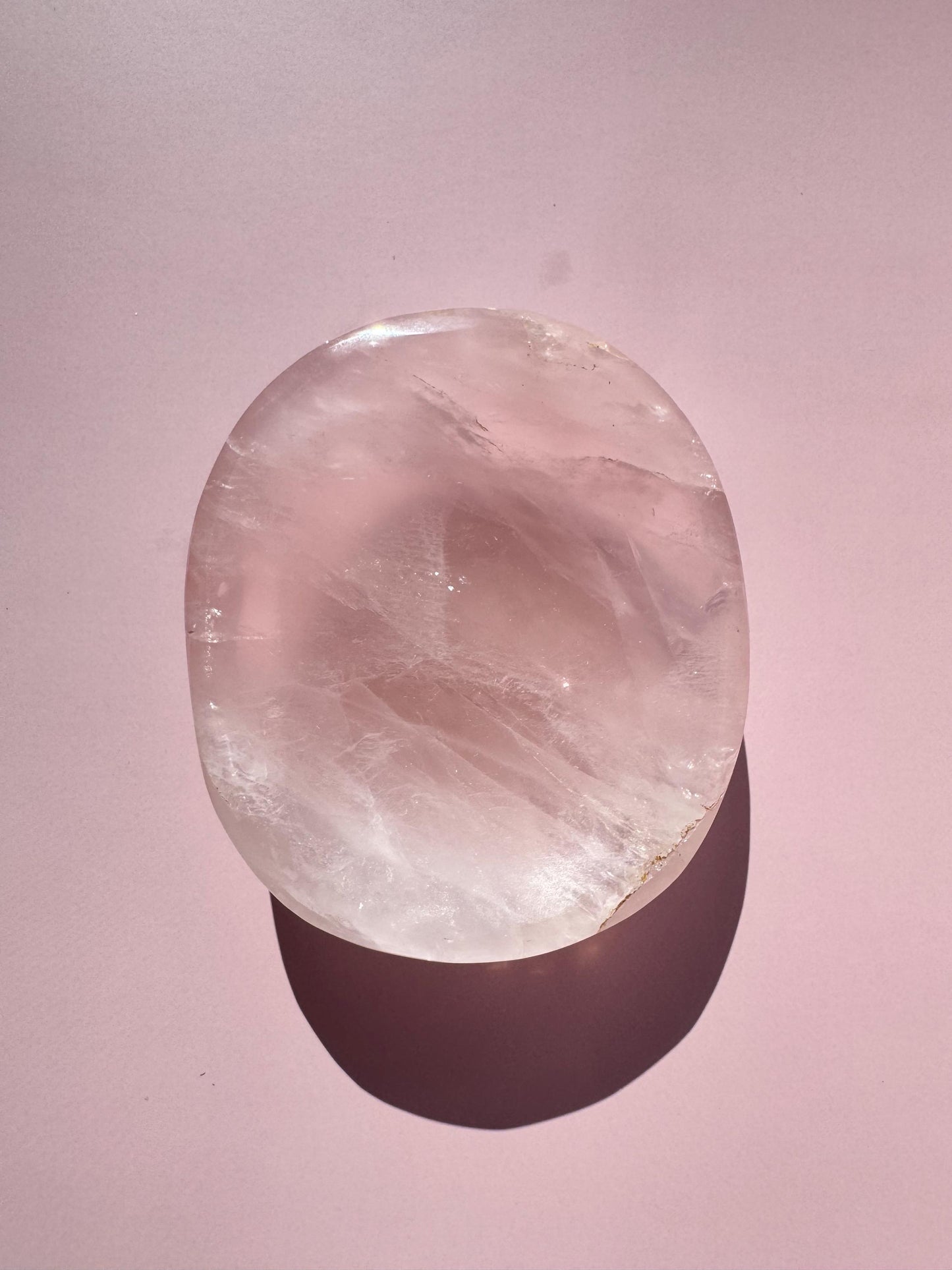 A polished Rose Quartz Bowl (ITEM B), crafted from pink crystal, sits on a pale pink surface, perfect for holding small tumbles, jewelry, or trinkets and casting a soft shadow.