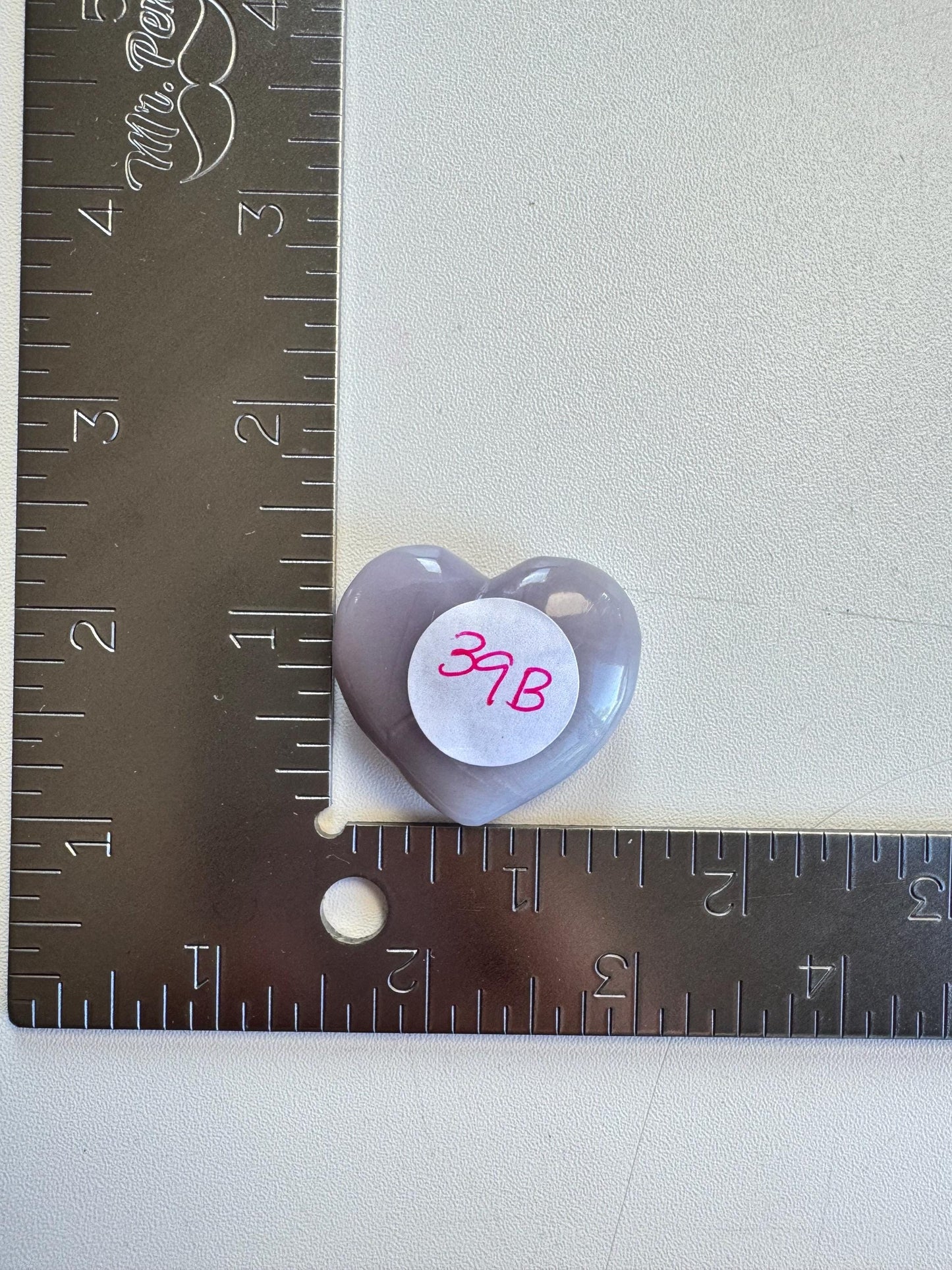 A Lavender Fluorite Heart Carving from Mexico ("37B") is shown beside a metal ruler marked in inches.