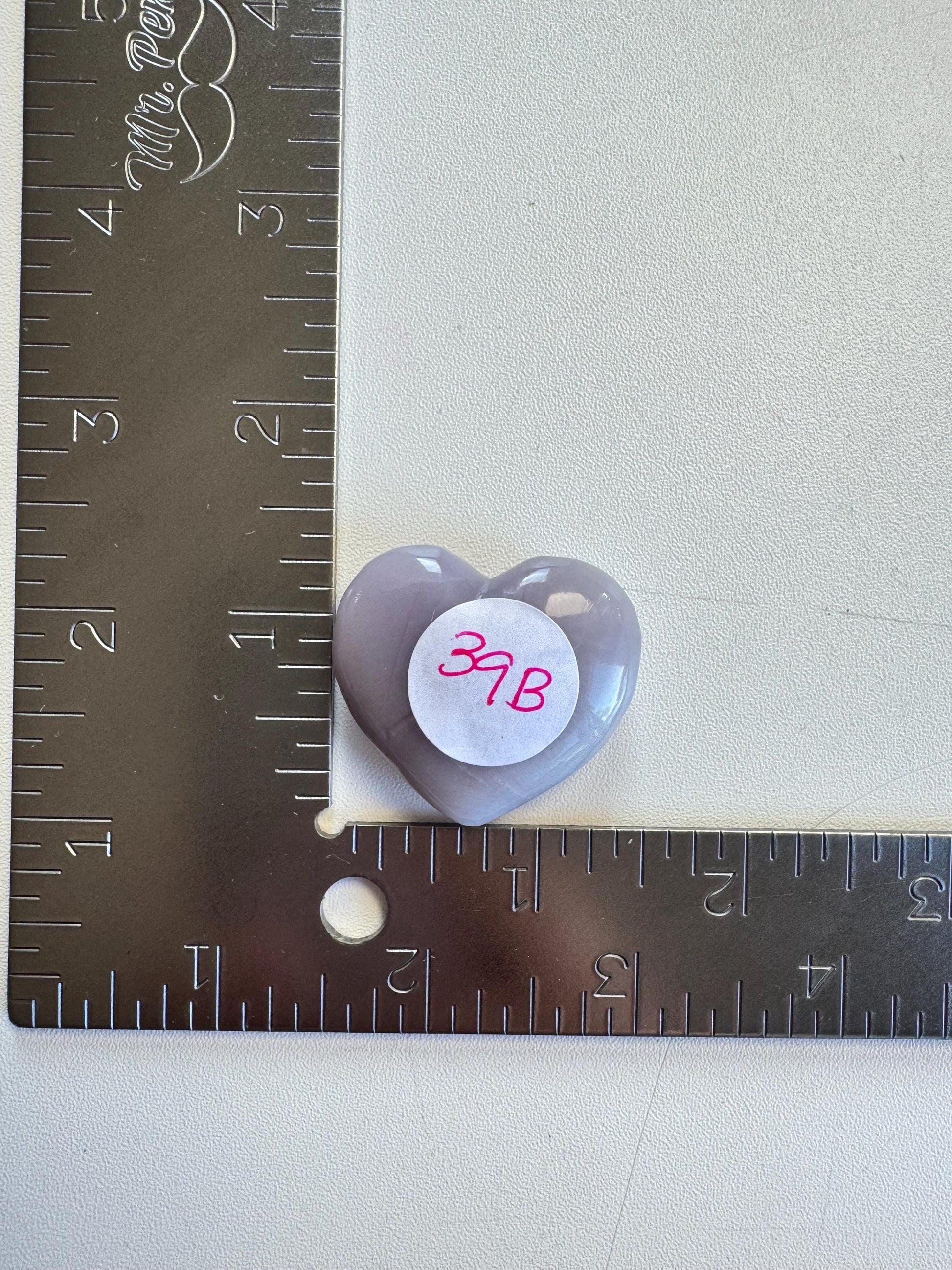 A Lavender Fluorite Heart Carving from Mexico ("37B") is shown beside a metal ruler marked in inches.
