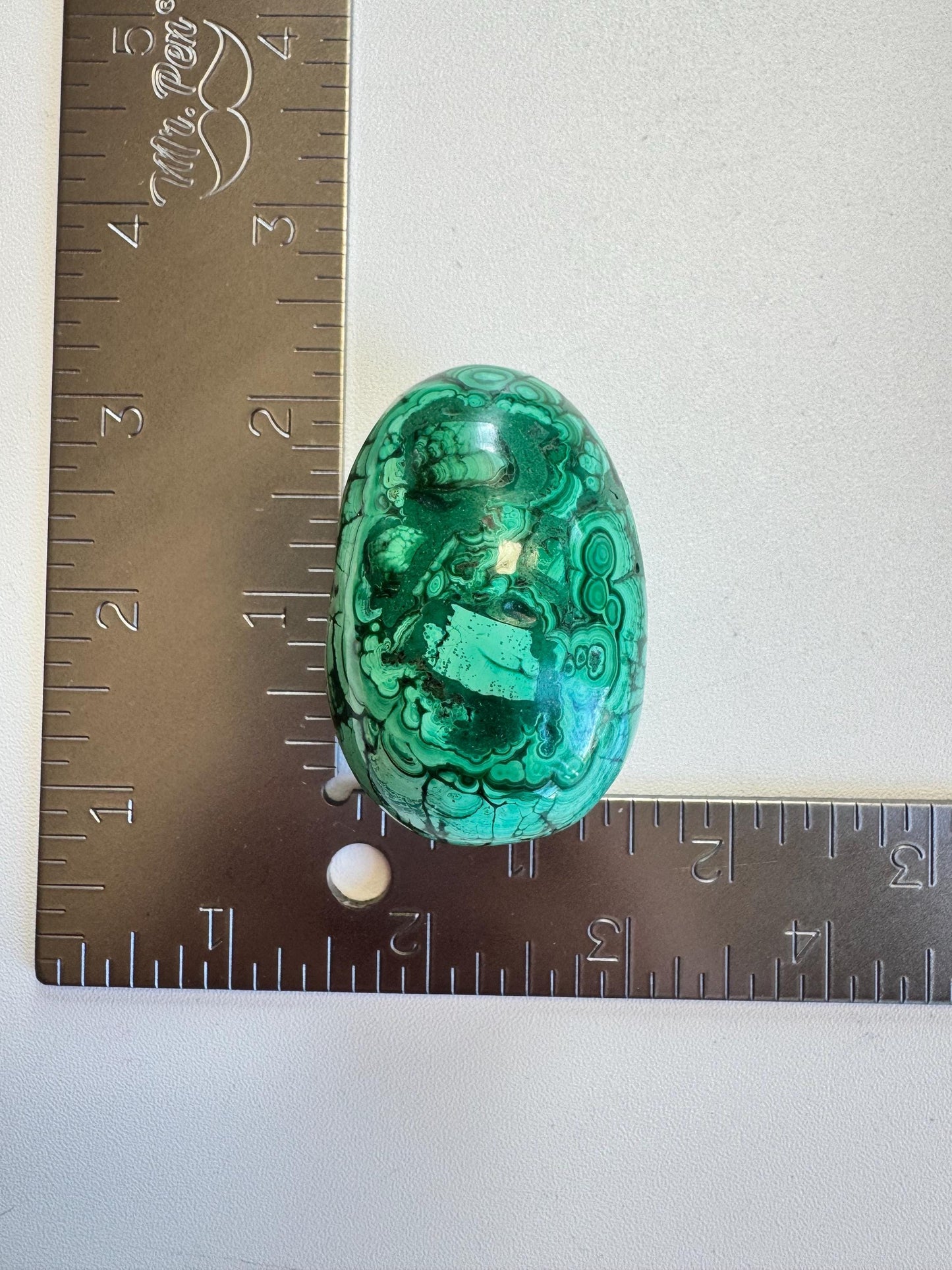 The Malachite Egg-Shaped Carving (ITEM C) features swirling green patterns and measures about 2 inches long by 1.5 inches wide—a captivating transformation stone prized in crystal healing collections.